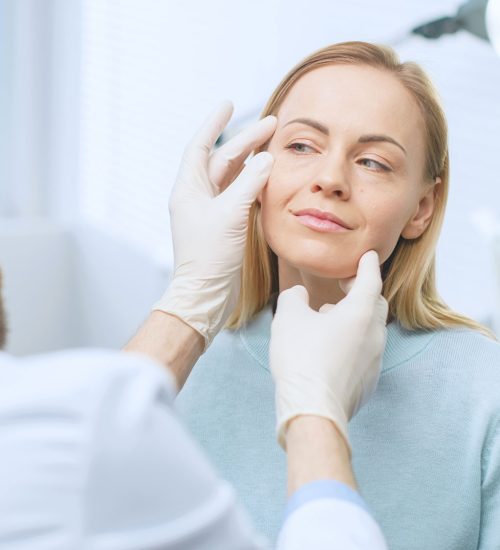 Doctor examining patient by touching forehead of woman in a clinic | Radiance Medical Spa in Coralville IA